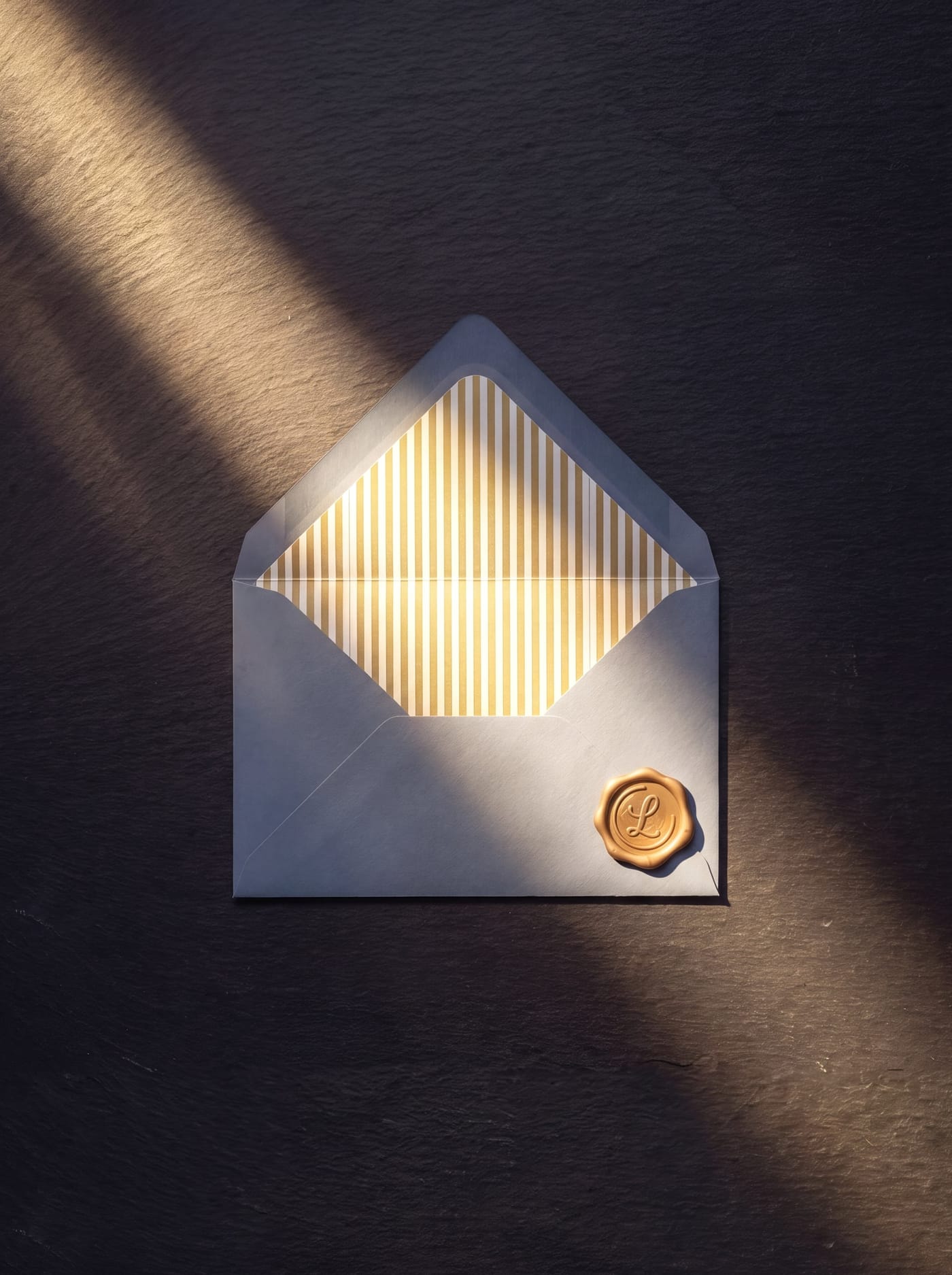 A cream envelope with a gold wax seal glowing in a shaft of sunlight against a dark stone background